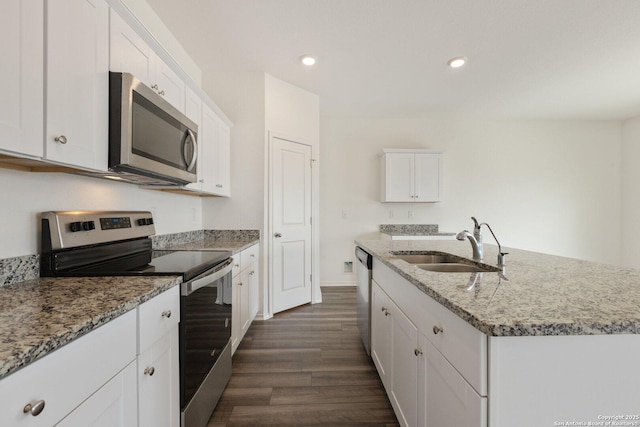 kitchen with dark wood-style flooring, a sink, an island with sink, white cabinets, and appliances with stainless steel finishes