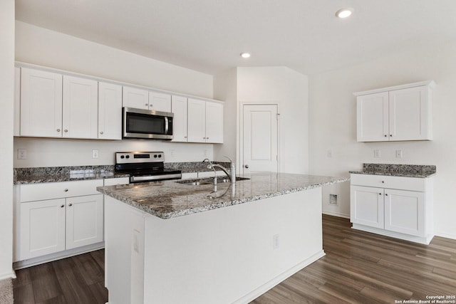 kitchen featuring dark wood finished floors, dark stone countertops, a sink, and stainless steel appliances
