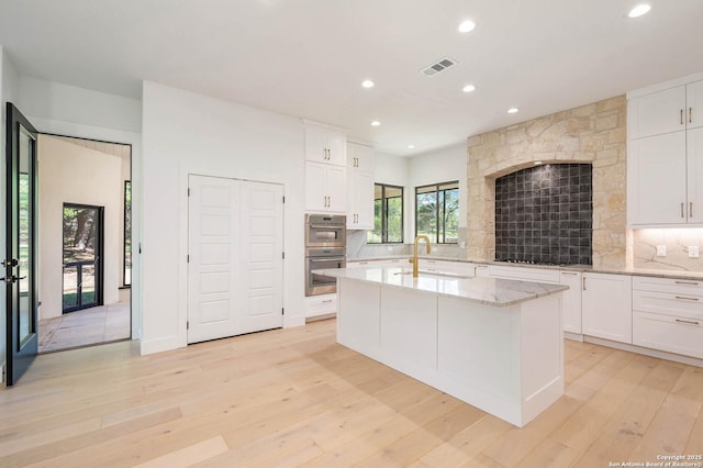 kitchen featuring recessed lighting, light wood-style flooring, double oven, a sink, and visible vents