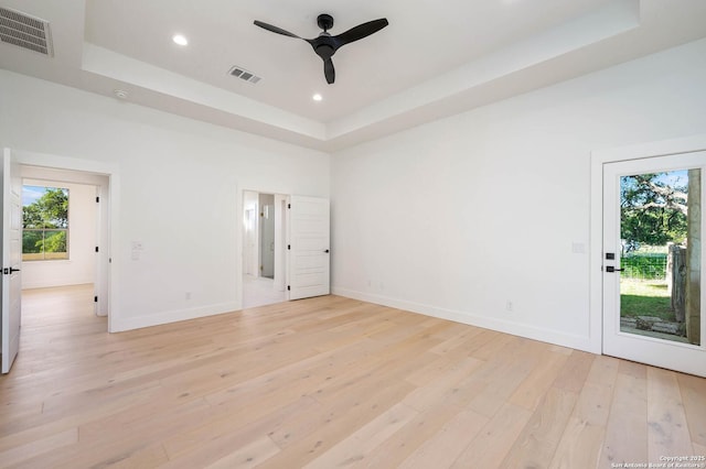 unfurnished room featuring a raised ceiling, visible vents, light wood-type flooring, and recessed lighting
