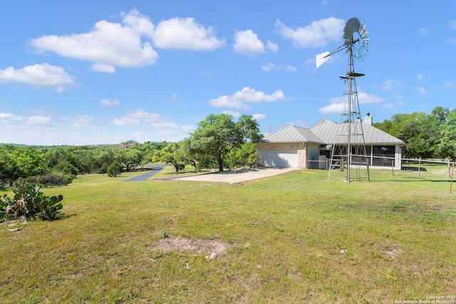 view of yard featuring a garage, fence, and driveway