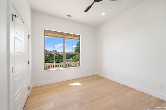 spare room featuring baseboards, a ceiling fan, and light wood-style floors