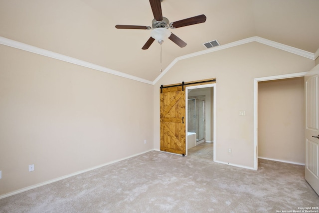 unfurnished bedroom with visible vents, carpet floors, baseboards, a barn door, and vaulted ceiling