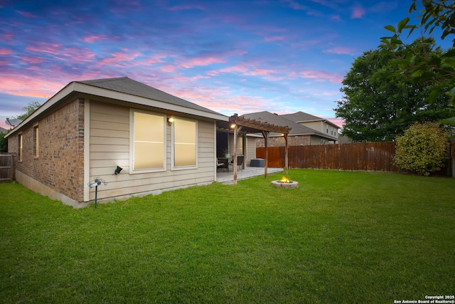 back of property at dusk featuring a lawn, a pergola, a fenced backyard, and a patio