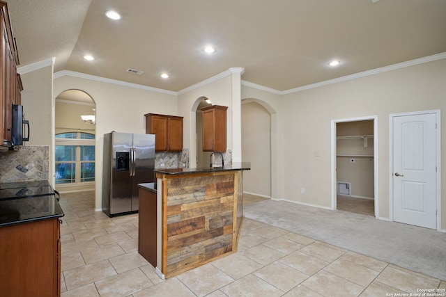 kitchen with stainless steel refrigerator with ice dispenser, arched walkways, light carpet, and a peninsula