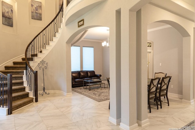 entrance foyer featuring crown molding, stairway, marble finish floor, baseboards, and arched walkways
