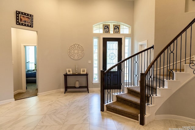 foyer entrance with marble finish floor, baseboards, a towering ceiling, and stairway