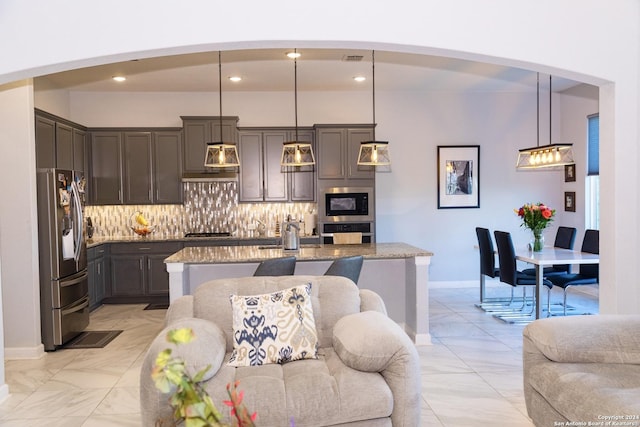 kitchen with decorative backsplash, light stone countertops, gas cooktop, stainless steel refrigerator with ice dispenser, and built in microwave
