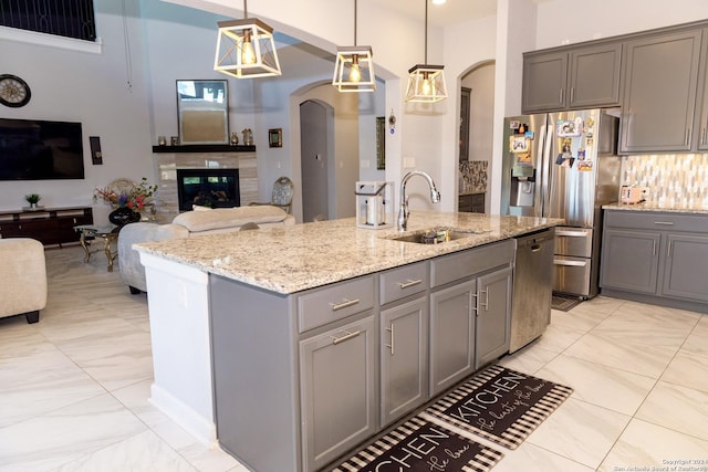 kitchen featuring appliances with stainless steel finishes, gray cabinetry, arched walkways, and a sink