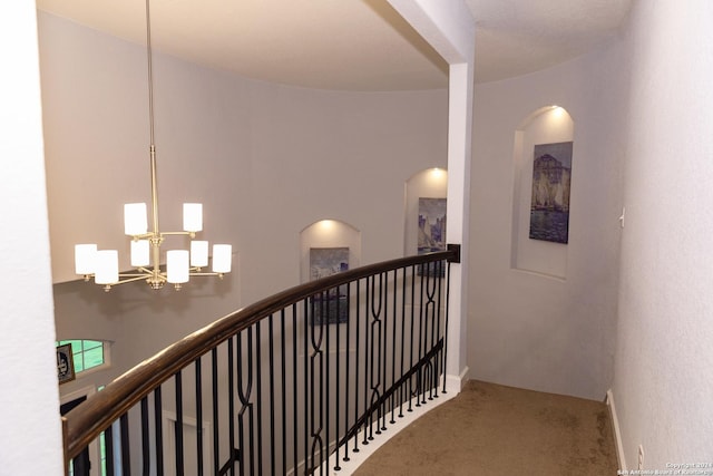 hall featuring carpet flooring, an upstairs landing, arched walkways, and a chandelier