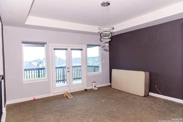carpeted empty room with baseboards, a tray ceiling, and french doors