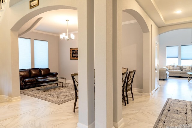 hallway with crown molding, marble finish floor, baseboards, arched walkways, and an inviting chandelier