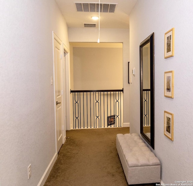 hall featuring baseboards, visible vents, and carpet flooring