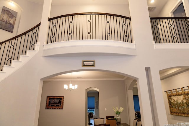 staircase featuring a high ceiling, ornamental molding, visible vents, and arched walkways