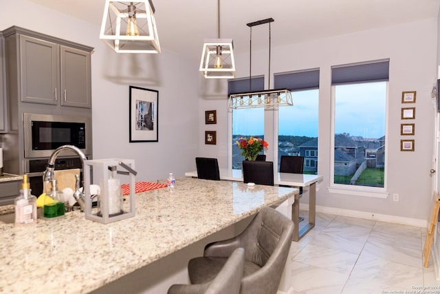 kitchen with marble finish floor, a kitchen bar, built in microwave, and gray cabinets