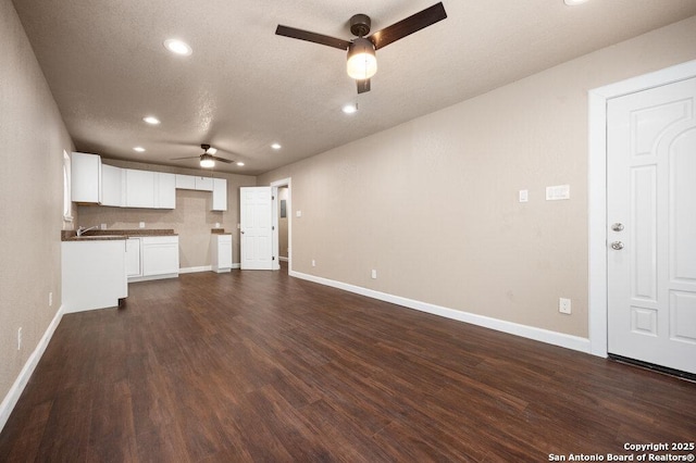 unfurnished living room with recessed lighting, dark wood-type flooring, baseboards, a textured ceiling, and ceiling fan