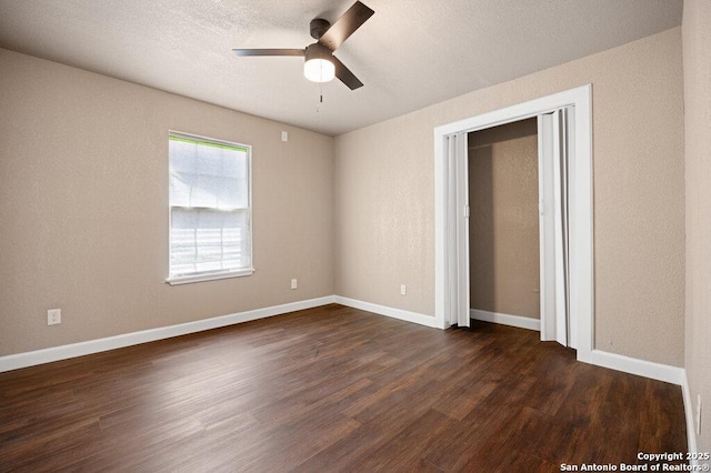 unfurnished bedroom featuring dark wood-style floors, a ceiling fan, baseboards, and a textured ceiling