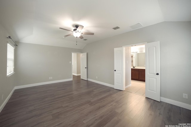 unfurnished bedroom featuring baseboards, visible vents, vaulted ceiling, and dark wood finished floors