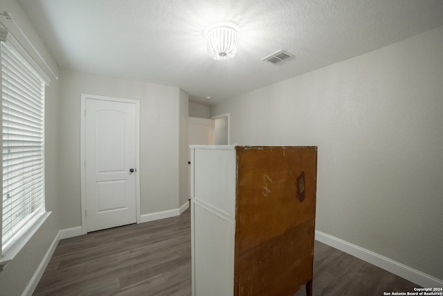 bedroom featuring dark wood finished floors, a textured ceiling, baseboards, and visible vents
