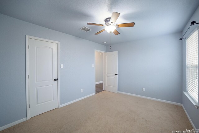 unfurnished bedroom featuring baseboards, ceiling fan, visible vents, and carpet