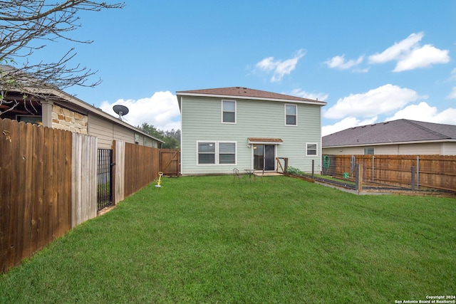 rear view of house featuring a lawn, a fenced backyard, and a vegetable garden