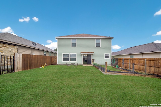 back of house featuring a fenced backyard, a lawn, and a garden