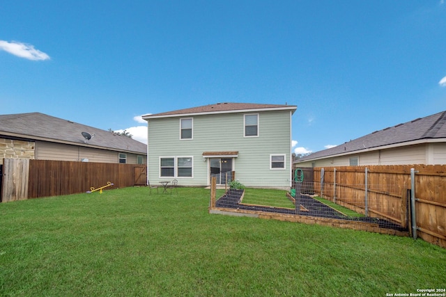 rear view of property with a fenced backyard, a lawn, and a vegetable garden