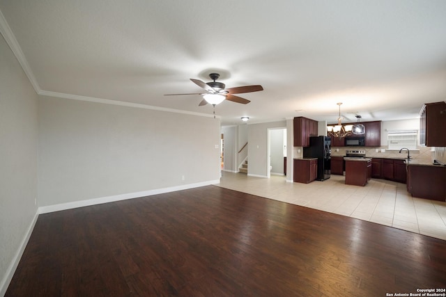 unfurnished living room featuring ceiling fan with notable chandelier, light wood-style flooring, a sink, and stairs