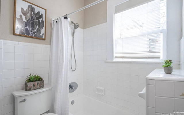 bathroom featuring toilet, a wainscoted wall, shower / tub combo, and tile walls