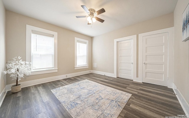 unfurnished bedroom featuring a ceiling fan, baseboards, and dark wood finished floors