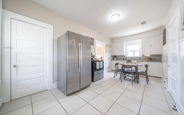 kitchen with light tile patterned floors, backsplash, visible vents, white cabinets, and appliances with stainless steel finishes