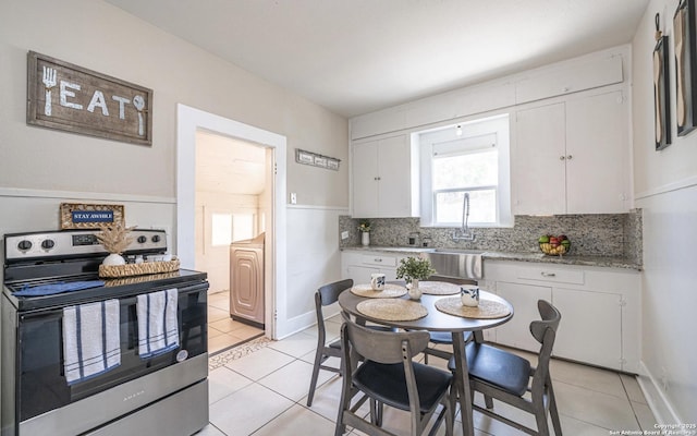 kitchen featuring a sink, tasteful backsplash, stainless steel electric range, and white cabinets
