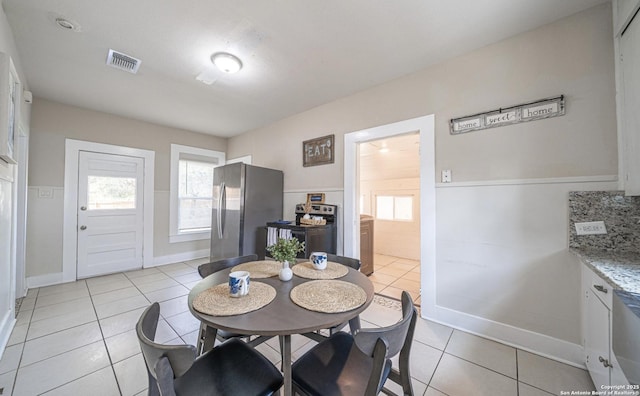 dining space featuring baseboards, visible vents, and light tile patterned floors