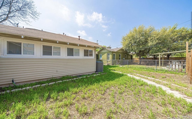 view of yard with central AC and fence