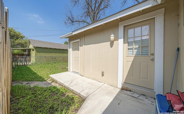 view of exterior entry featuring fence and a yard