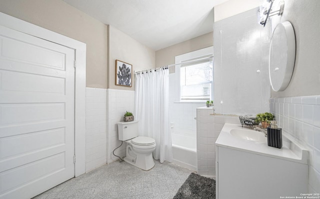 bathroom featuring tile walls, toilet, vanity, shower / tub combo with curtain, and wainscoting
