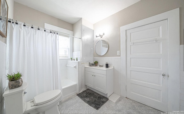 bathroom featuring tile walls, toilet, vanity, shower / bath combination with curtain, and wainscoting