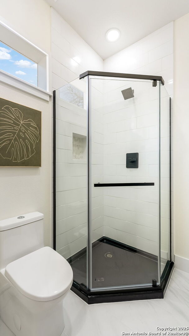 bathroom with toilet and a stall shower