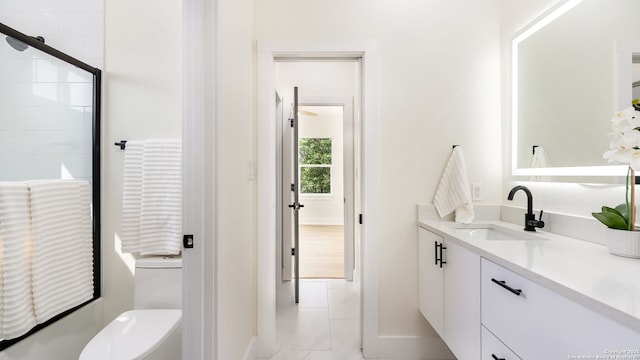 full bathroom featuring a shower with door, toilet, and vanity
