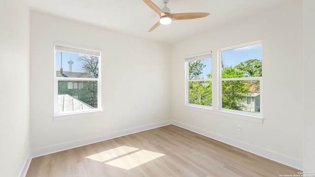 spare room with baseboards, light wood finished floors, and ceiling fan