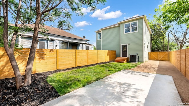 rear view of property featuring a gate, central AC unit, and fence