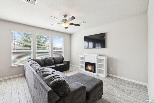 13850 Cohan Way, San Antonio, TX 78253 - living area featuring wood tiled floor, visible vents, ceiling fan, and a glass covered fireplace