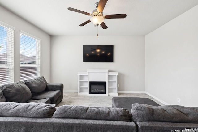 13850 Cohan Way, San Antonio, TX 78253 - living room with baseboards, a glass covered fireplace, light wood-style floors, and a ceiling fan