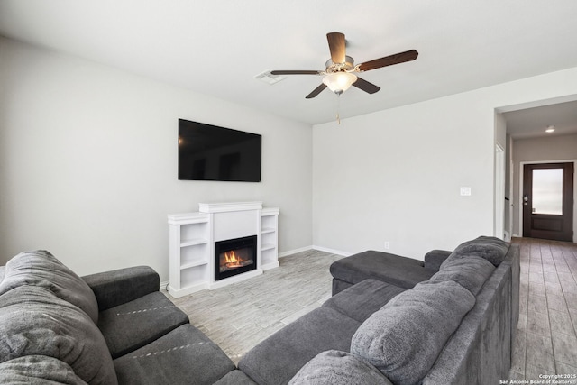 13850 Cohan Way, San Antonio, TX 78253 - living room with visible vents, baseboards, ceiling fan, wood finished floors, and a glass covered fireplace
