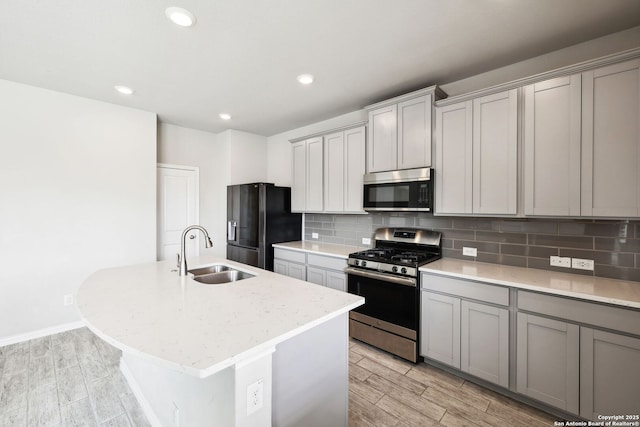 13850 Cohan Way, San Antonio, TX 78253 - kitchen featuring appliances with stainless steel finishes, an island with sink, a sink, gray cabinetry, and backsplash