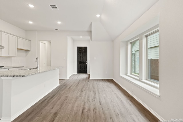kitchen with light stone counters, recessed lighting, white cabinets, light wood-style floors, and visible vents