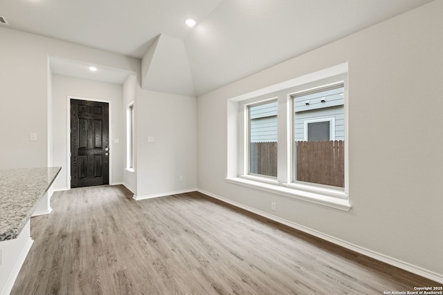 interior space with light wood-style flooring, recessed lighting, vaulted ceiling, and baseboards