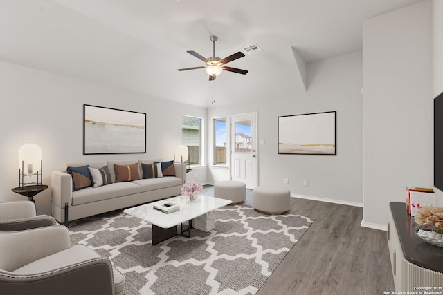 living area featuring visible vents, baseboards, a ceiling fan, and wood finished floors