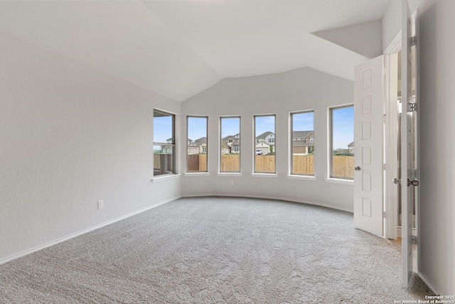 empty room featuring carpet, baseboards, and vaulted ceiling