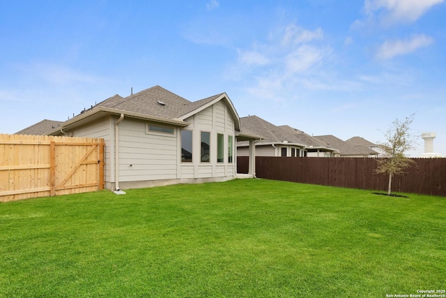 back of property featuring a shingled roof, fence private yard, and a lawn